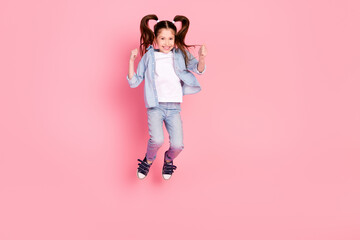 Full size photo of excited positive lovely small girl dressed denim shirt pants jumping having fun isolated on pink color background