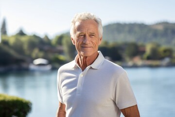Portrait of a blissful man in his 80s wearing a sporty polo shirt in front of serene lakeside view