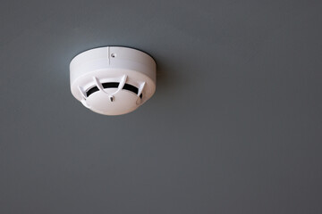 A white smoke detector is hanging from the ceiling