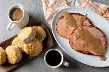 Overhead shot of Traditional Ohio Foods - Red-Eye Gravy with Ham and Biscuits with a coffee cup and gravy pourer
