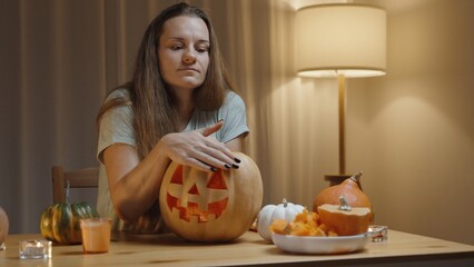 Warm Home Setting for Halloween, the Woman Proudly Showing the Carved Jack-o'-Lantern from the Pumpkin, Stroking It with Her Hand.