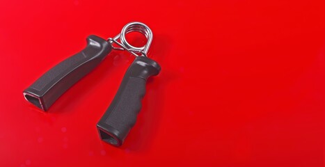 Hand exercise gripper isolated on red background.  Panoramic image with copy space. 