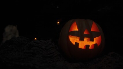 Jack-O'-Lantern Pumpkin for Halloween with Burning Light Inside Stands in a Dark Cave on the Rocks....