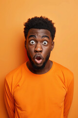 Surprised man wearing bright orange shirt with wide eyes and open mouth against an orange background. Shocked expression, vibrant and colorful portrait.