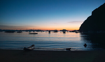 Silhouetted boats at sunset in el nido, palawan