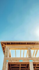 Wooden frame of a building under construction against a clear blue sky