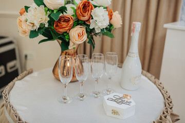 A table with a vase of flowers, four wine glasses, and a white box with the word love written on it