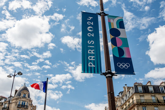 Paris, France - 25 juillet 2024 : Banni&egrave;res verticales, panneaux d&eacute;coratifs color&eacute;s pour les Jeux olympiques d'&eacute;t&eacute; de Paris 2024 avec un drapeau fran&ccedil;ais flottant &agrave; l'arri&egrave;re-plan