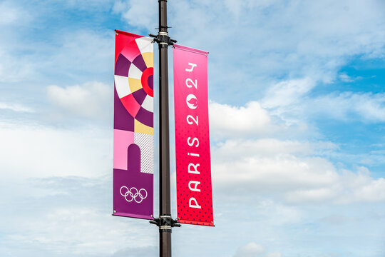 Paris, France - 25 juillet 2024: Drapeau enseigne verticale, banni&egrave;re d&eacute;corative color&eacute;e &agrave; l'occasion des Jeux olympiques d'&eacute;t&eacute; de Paris 2024 dans une rue de Paris avec le ciel en arri&egrave;re-plan