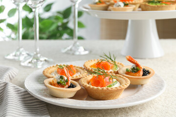 Delicious canapes with shrimps, salmon and caviar on beige textured table, closeup