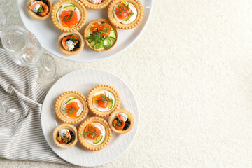 Delicious canapes with shrimps, salmon and caviar on beige textured table, flat lay. Space for text
