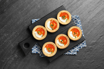 Delicious canapes with shrimps, red caviar and cream cheese on dark textured table, top view