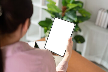 Woman Holding Blank Tablet Screen in Modern Home Office with Green Plants and Bookshelves