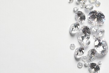 Many beautiful shiny diamonds on white background, flat lay. Space for text