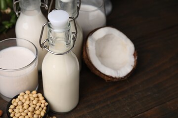 Different types of vegan milk and ingredients on wooden table, closeup