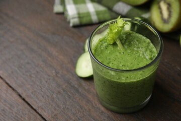 Tasty green smoothie in glass on wooden table, closeup. Space for text