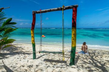 Woman sitting near a colorful swing on the scenic tropical sandy Anse Source d'Argent beach, La Digue island, Seychelles