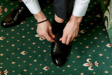A man is putting on his shoes, and the image conveys a sense of formality and attention to detail