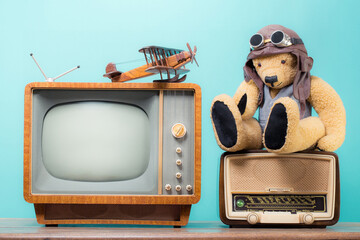 Retro TV, vintage radio, Teddy Bear and wooden plane toys front mint blue background. Old style...