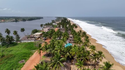aerial view of a beach with palm trees and waves heating the beach in Ivory Coast