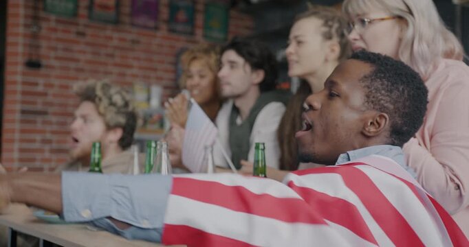 Group of sports fans with American flags watching baseball game cheering feeling unhappy and disappointed indoors at home. Fans and emotion concept.