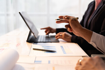 Businessman and woman discussing commercial real estate sector faces risks as financial buy used laptop calculator and chart in the office.