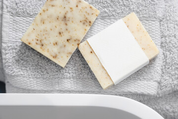 Soap bars with blank label on light grey towels near vessel sink in bathroom closeup, mockup