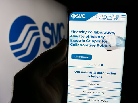 Stuttgart, Germany - 07-25-2024: Person holding smartphone with webpage of Japanese machinery company SMC Corporation in front of business logo. Focus on center of phone display.