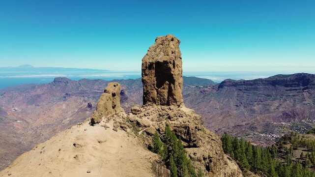 Aerial view of people hiking in Gran Canaria at Roque Nublo mountain geologic rock formation. Drone view of Teide and Tejeda in the background