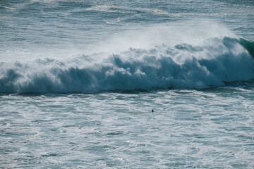 A large ocean wave crashing powerfully against the shore, showcasing the force and dynamic nature of the sea.