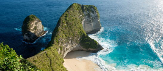 Aerial view of stunning coastal rock formations surrounded by deep blue ocean water and lush greenery.