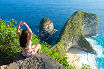 A lone traveler stands on a sun-drenched rock overlooking the vast blue Mediterranean Sea
