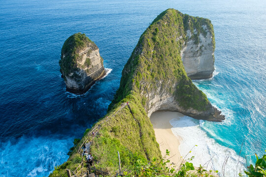 Aerial view of stunning coastal rock formations surrounded by deep blue ocean water and lush greenery.