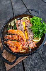 Healthy baked salmon steaks with greens and asparagus in a black cast iron skillet. A delicious low-carb breakfast.