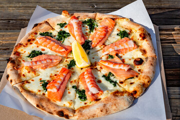 Pizza with shrimp and seafood on the table in a beautiful place.
