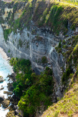 A cliffside path with a breathtaking view of the blue ocean and lush greenery, ideal for adventurers and nature lovers.