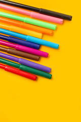 Marcadores de colores sobre un fondo amarillo. Vista superior y de cerca. Copy space. Formato vertical