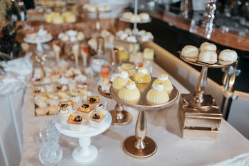 A table full of desserts including cakes, cupcakes, and pastries. The table is set up for a party or event