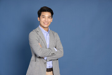Happy young Asian startup businessman smiling in blue studio isolated background