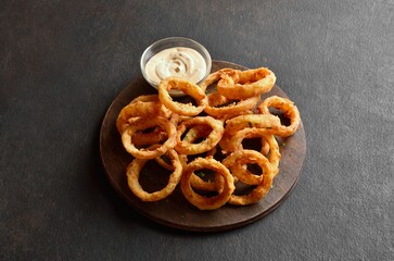 Heap of deep fried onion rings on wooden serving dish
