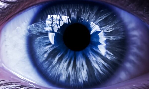 Close up: A human eye changes color, morphing through the powerful colors. Inside the eye, particles fluoresce, enhancing the vibrant transformation. Cinematic.