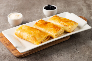 Thin pancakes stuffed with cottage cheese served with sour cream and black currant jam. French crepes. 