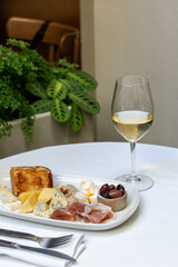 Elegant cheese and charcuterie platter with white wine on a table. Concept of gourmet dining, culinary indulgence, and fine wine pairing. High quality photo
