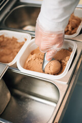 The seller puts a ball of ice-creamby scoop