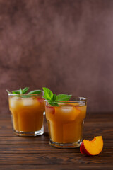 Refreshing peach ice and mint tea on a wooden table. Homemade cold summer drink. Vertical orientation.