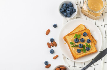 Toast with peanut butter, blueberries and almond. Sandwich and ingredients for breakfast top view with copy space