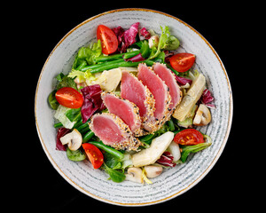 Salad with tuna and artichokes on a black background for the restaurant menu