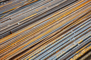 Close-up of steel rebar at a construction site. The textured bars are aligned and ready for use in reinforced concrete structures, showcasing the strength and precision of modern engineering.