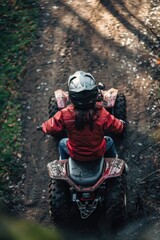 Woman is riding red ATV on dirt road