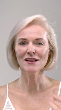 Old woman holds a yellow capsule or medicine tablet in her hand. Senior female takes dietary supplements, puts the drug or pill in her mouth. Lady takes care of the beauty of the body, rejuvenation